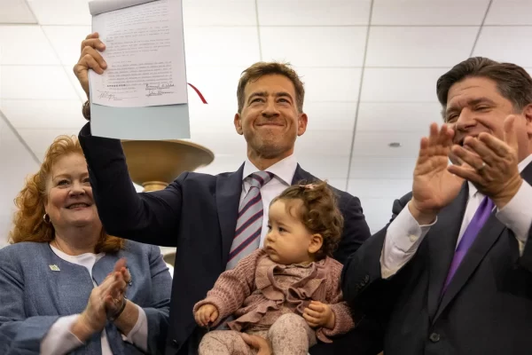 Secretary of State Alexi Giannoulias holding up the newly signed bill at Harold Washington Library.